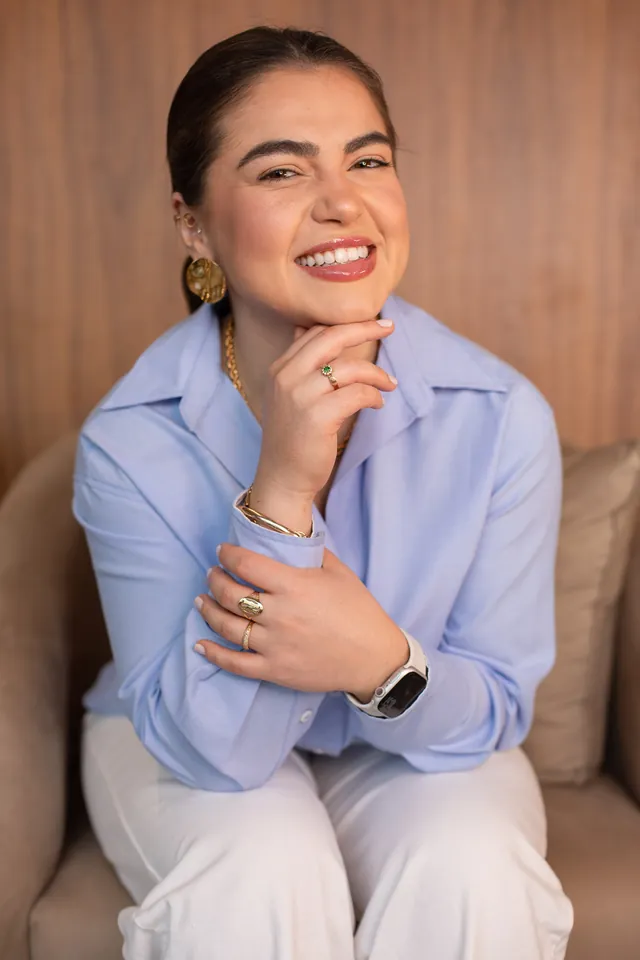 Nathália Alves sorrindo, sentada em um sofá
